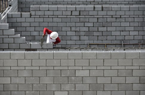 Bricklayer working on brick wall.