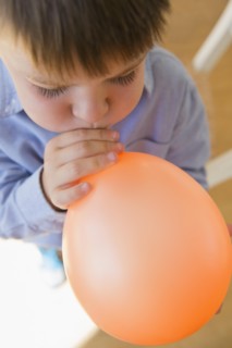 Boy (6-7) inflating balloon