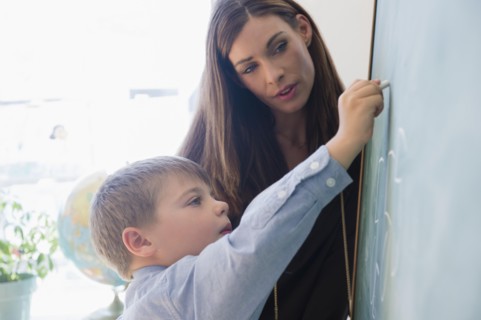 Female teacher and schoolboy (6-7) in classroom