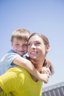 Mother giving her son (6-7) piggyback ride