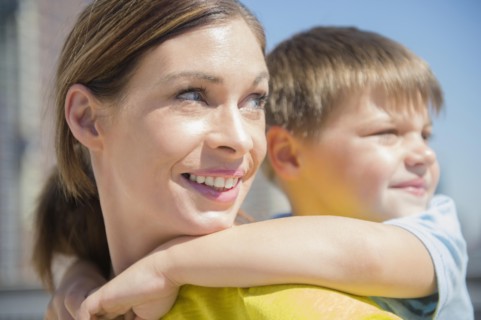 Mother giving her son (6-7) piggyback ride