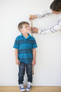 Mother measuring son (6-7) with ruler