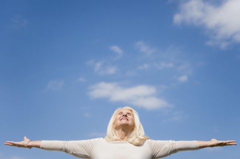 Upward view of senior woman with arms outstretched