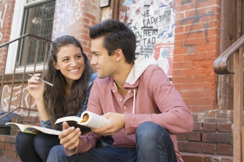 Young couple reading book and doing crossword