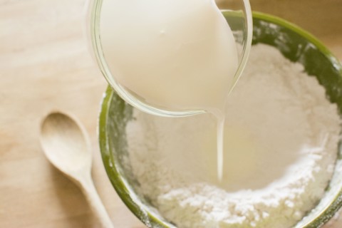 Pouring milk into bowl with flour