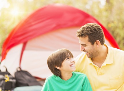 Portrait of father and son (12-13) camping