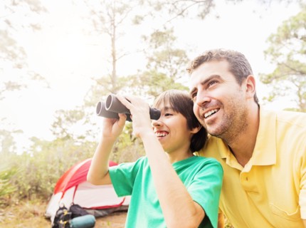 Father and son (12-13) using binoculars