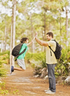Father and son (12-13) doing high five in forest
