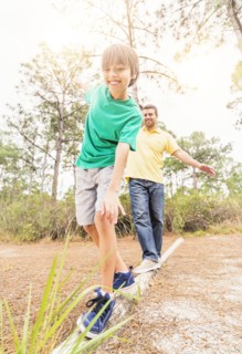 Father and son (12-13) balancing on log