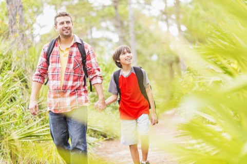 Father and son (12-13) walking in forest