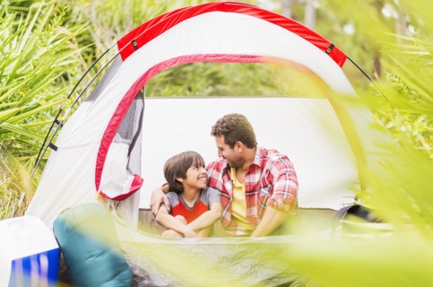 Father and son (12-13) sitting in tent