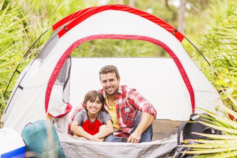 Father and son (12-13) sitting in tent