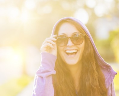 Portrait of smiling woman in hoodie with sunglasses