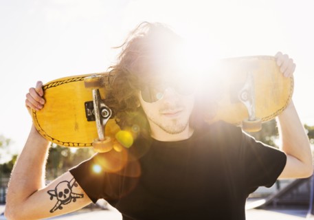 Man holding skateboard on his arms