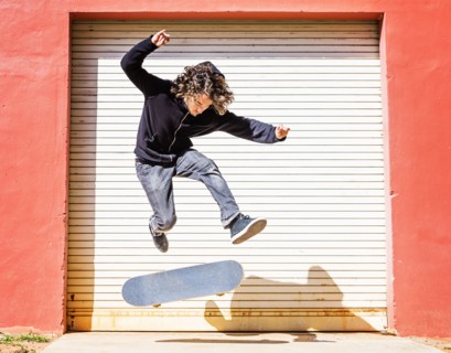 Man jumping on skateboard against closed garage door
