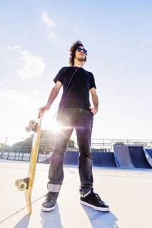 Man leaning on skateboard in skatepark