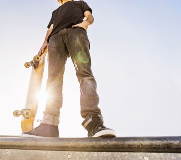 Man leaning on skateboard in skatepark
