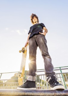 Man leaning on skateboard in skatepark