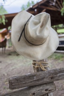 Cowboy hat hanging on wooden fence
