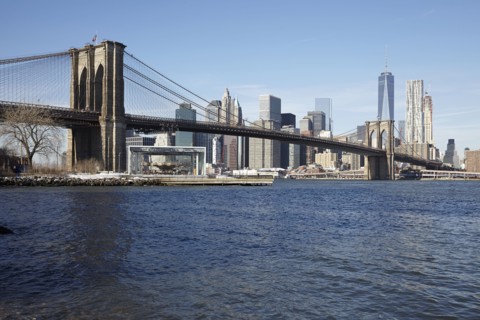 View of waterfront cityscape with suspension bridge