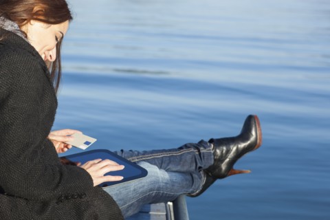 Woman with tablet by lake