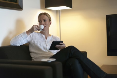 Woman using digital tablet and drinking coffee at home