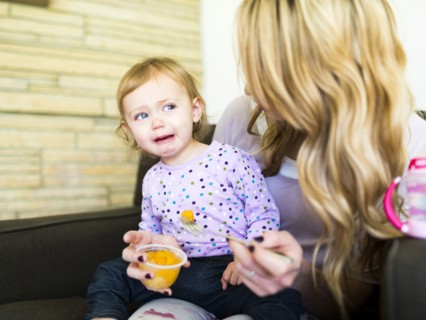 Woman feeding her daughter (12-17 months)