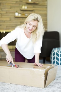 Young woman opening box with scissors