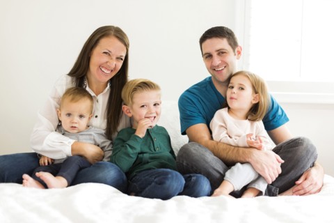 Portrait of family with three children (2-3, 4-5) sitting on bed