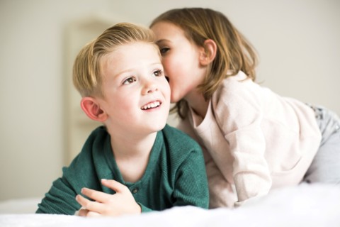 Siblings (2-3, 4-5) whispering in bedroom