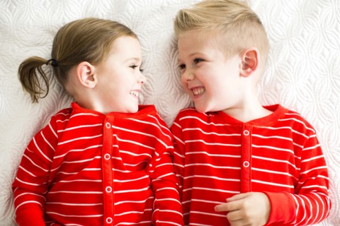 Siblings (2-3, 4-5) in red pajamas lying on bed