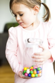 Girl (4-5) holding glass jar with candies