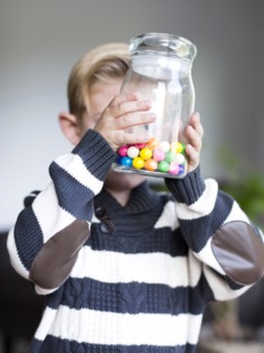 Boy (6-7) holding glass jar with candies