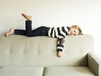 Boy (6-7) lying on sofa