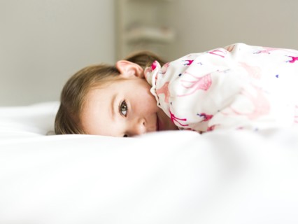 Girl (2-3) lying on bed