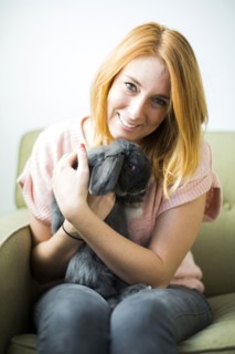 Woman sitting on sofa embracing rabbit