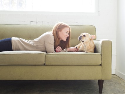 Woman and pug lying on sofa