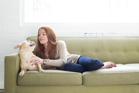 Woman lying on sofa stroking pug
