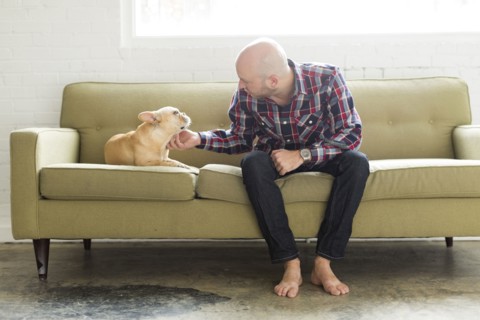 Man sitting on sofa stroking pug