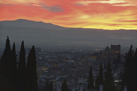 Cityscape and hill at sunset, red yellow sky
