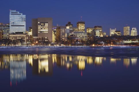 Illuminated cityscape reflecting in water at dusk