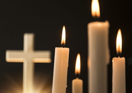 Burning candles with cross in background.
