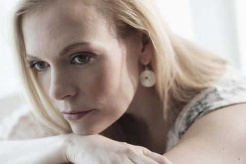 Pensive mid-adult woman lying on bed.