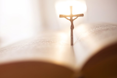 Backlit cross in open Bible.
