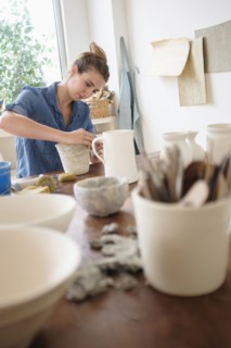 Young woman making pottery in studio.