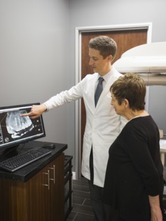 Dentist showing patient x-ray on computer screen