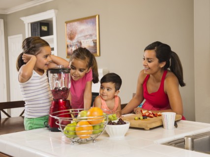 Mother and children (2-3, 6-7, 8-9) preparing fruit cocktails