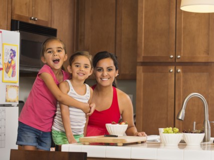 Mother and children (6-7, 8-9) preparing food in kitchen