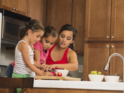 Mother and children (6-7, 8-9) preparing food in kitchen