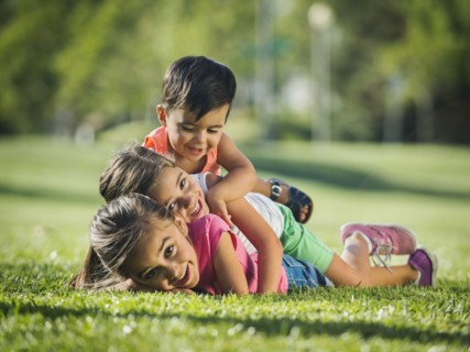 Children (2-3, 6-7, 8-9) playing in park